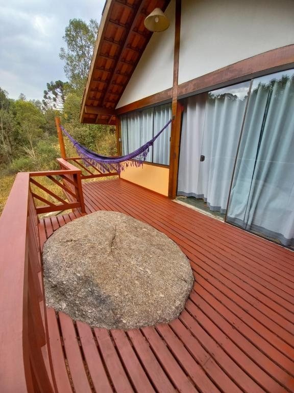 Deck de madeira com rede e uma rocha natural integrada